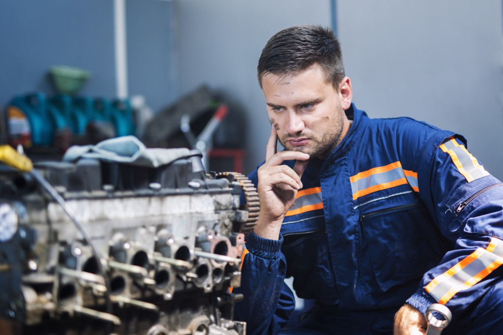 professional experienced car mechanic repairman uniform thinking about solution looking car engine mechanics workshop 1